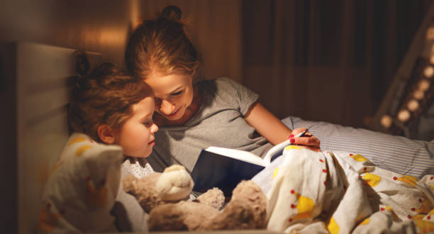 mother and child reading book in bed before going to sleep mother and child daughter reading book in bed before going to sleep 8571 stock pictures, royalty-free photos & images