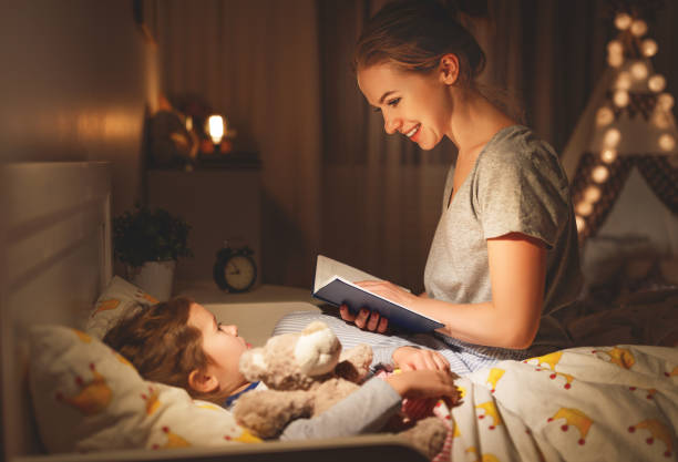 mother and child reading book in bed before going to sleep mother and child daughter reading book in bed before going to sleep bedtime stock pictures, royalty-free photos & images