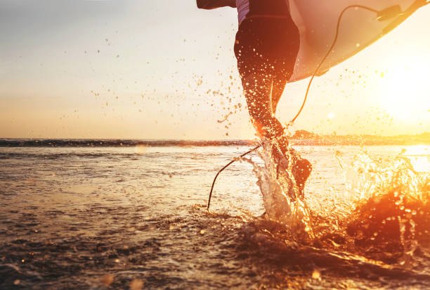 istock Closeup image water splashes from surfer's legs run in ocean with surfboard 965218366