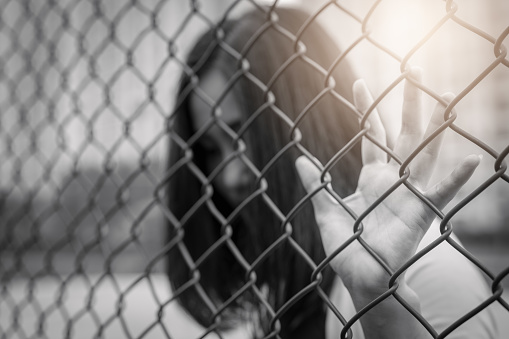 Depressed, trouble, help and chance. Hopeless women raise hand on chain-link fence ask for help