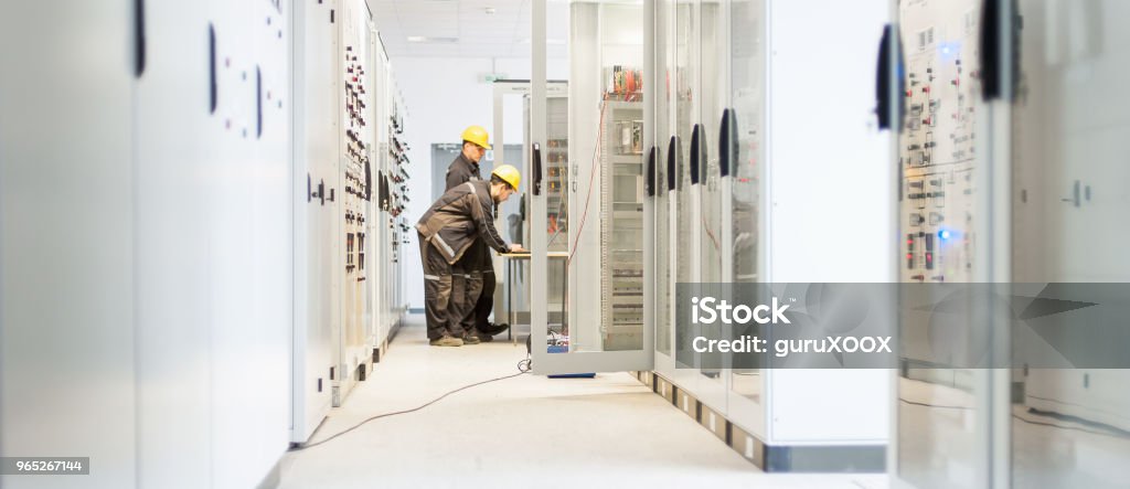 Field service crew testing electronics or inspecting electrical installation system Field service crew testing electronics or inspecting electrical installation system. Bay control unit. Medium voltage switchgear Repairing Stock Photo