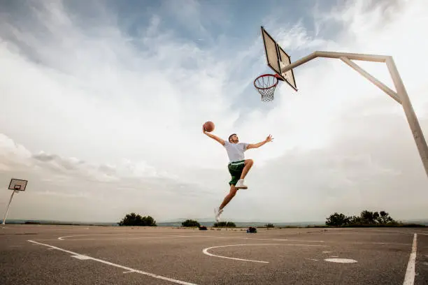 Photo of Man playing basketball and doing a slam dunk