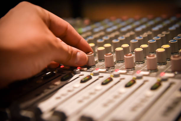 istock close-up hands of sound engineer adjusting audio mixer controller for live music and studio equipment. This is a quality audio system for professionals. vintage tone & effect light in control room. 965276796