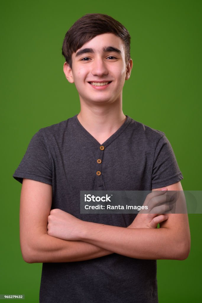 Young handsome Iranian teenage boy against green background Studio shot of young handsome Iranian teenage boy against chroma key with green background Iranian Ethnicity Stock Photo