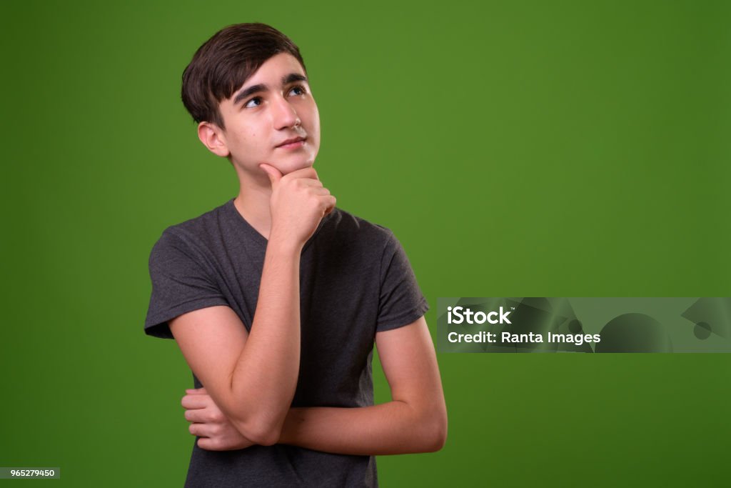 Young handsome Iranian teenage boy against green background Studio shot of young handsome Iranian teenage boy against chroma key with green background Green Screen Stock Photo