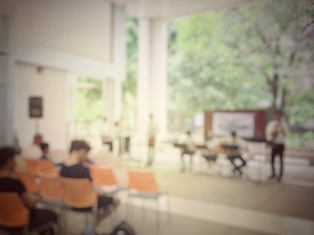 Silhouette of a man sitting alone in an empty hospital waiting room behind frosted glass, creating a sense of solitude.