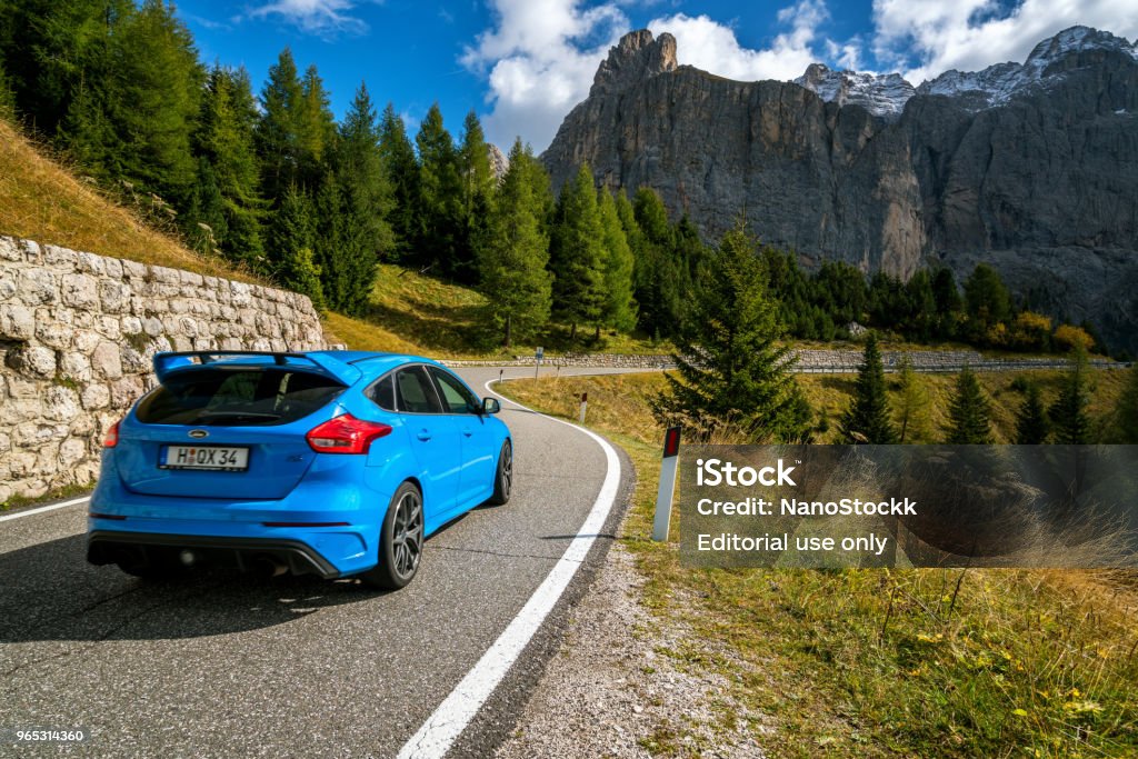 Car drives on mountain road in Dolomites, Italy. Bolzano, Italy - Sep 27, 2017: Blue Ford car drives on mountain road in northwestern Dolomites mountain in Italy. Dolomites or Dolomiti mountains are famous for adventure travel, trekking and hiking. Car Stock Photo