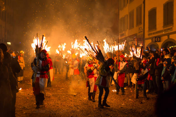 Chienbaese parade in Liestal Chienbaese festival. Switzerland, Liestal, Rathausstrasse 25, 18th of February 2018. Festival participants carrying burning broom shaped wooden logs on their shoulders through the old town. fasnacht festival stock pictures, royalty-free photos & images