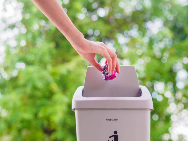 istock female hand trowing a paper into a garbage bin on bokeh background. cleaning concept. 965331606