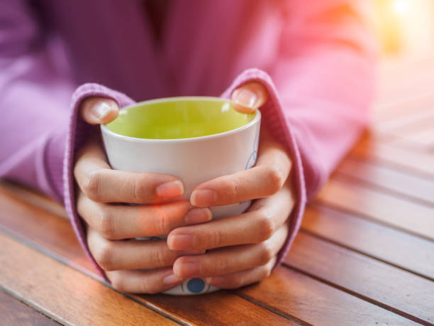istock Female hand holding a cup on wooden table. 965333738