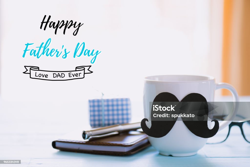 Happy fathers day concept. beautiful gift box, glasses, notebook, pen and coffee cup with black mustache on wooden table background. Adult Stock Photo