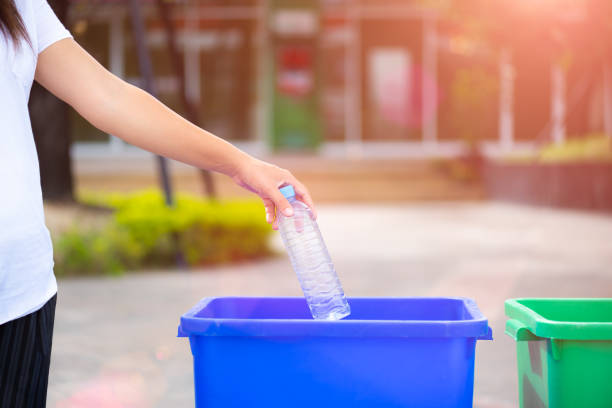 istock World Environment Day, June 5. Woman hand holding and putting plastic bottle waste into garbage trash. 965334368