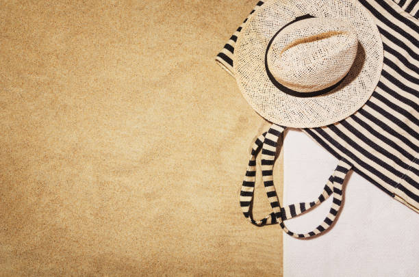 Top view of sandy beach with towel frame and summer accessories. Background with copy space and visible sand texture. Border composition made of towel