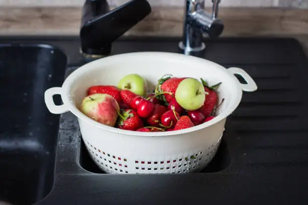 Ripe Fresh Berries and Fruits in black kitchen-sink. Summer Food Concept