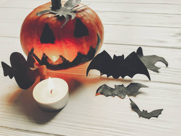 istock halloween. jack lantern pumpkin with witch ghost bats and spider black decorations on white wooden background top view. seasonal greetings. happy halloween concept, holiday celebration 965345960