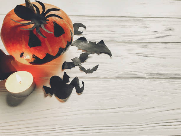 istock halloween. jack lantern pumpkin with witch ghost bats and spider black decorations on white wooden background top view. seasonal greetings. happy halloween concept, holiday celebration 965348730