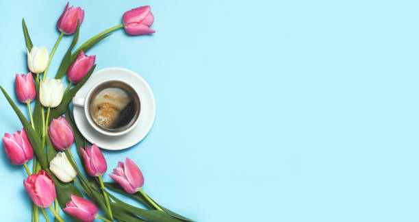 istock Cup of coffe and pink tulips on blue background. 965353134