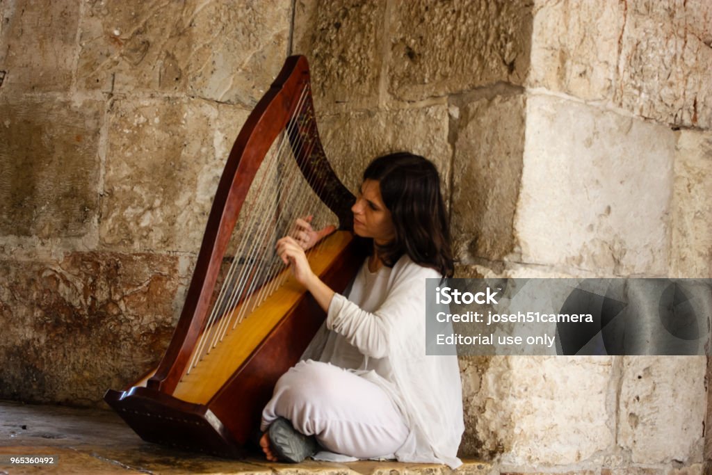 colors of Israel Jerusalem Israel May 28, 2018 View of a street musician playing Harp at the Jaffa Gate in the Old City of Jerusalem in the afternoon Adult Stock Photo