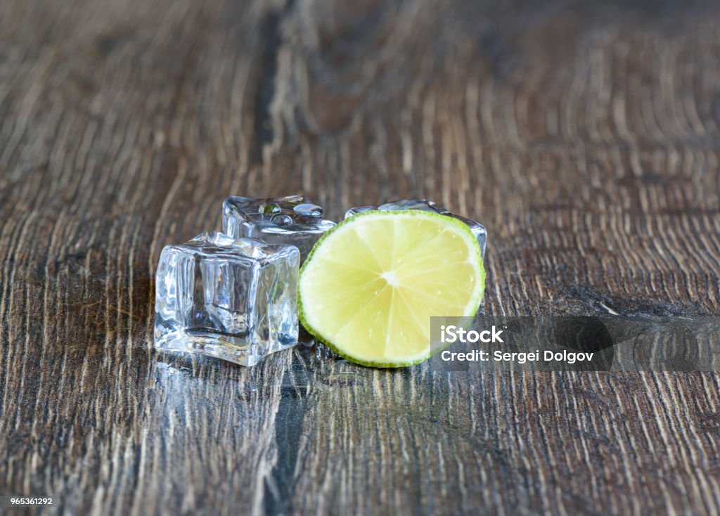 Cubes of ice and slice of lime in a wooden table Cubes of ice and slice of lime in a wooden table. Close up Citrus Fruit Stock Photo