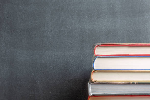 istock Stack of book resting in front of a chalkboard 965375070