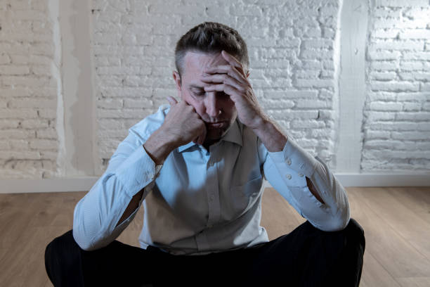 istock depressed business man feeling sad, lonely and suffering from anxiety leaning on a white wall at home in mental health depression concept 965384480