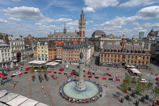 Lille France July 21 2018: c view of Grand Place, city central square from the Theatre du Nord with monument, old stock exchange building, shops with people walking to work & on holiday