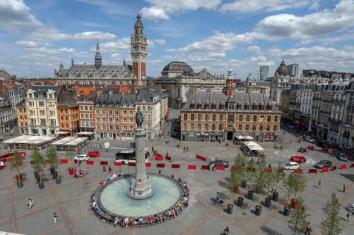 Lille France July 21 2018: c view of Grand Place, city central square from the Theatre du Nord with monument, old stock exchange building, shops with people walking to work & on holiday