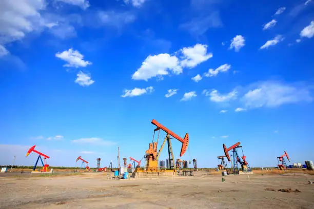 At the oil field, the oil pump is running, blue sky and white clouds. Timelapse