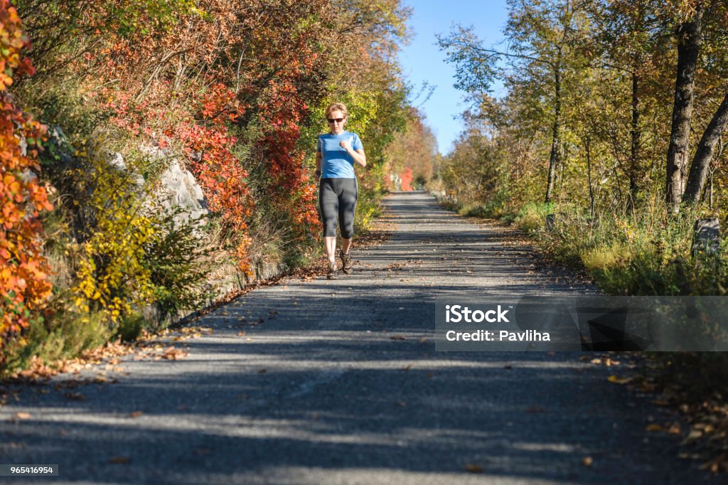 Caucasian mature woman running at sunset in autumn, Italy, Europe Caucasian mature woman running at sunset in autumn, Italy, Europe,no logos,Nikon D3x Active Lifestyle Stock Photo