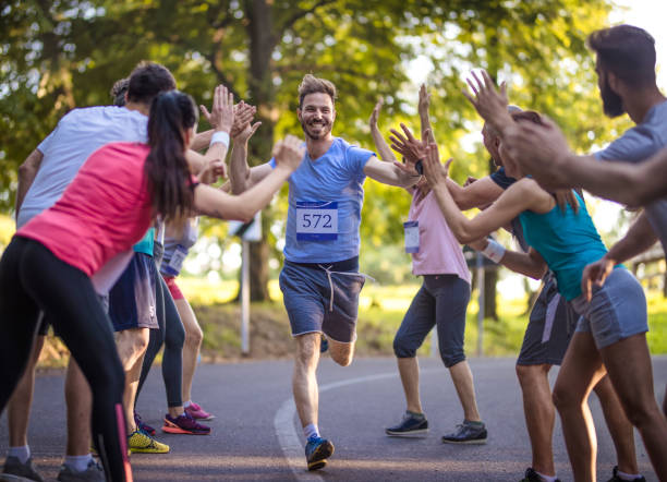 счастливый марафонец приветствие группы спортсменов на финише. - distance running фотографии стоковые фото и изображения