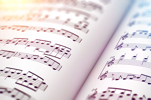 Creative abstract musical concept background: 3D render illustration of the macro view of white score sheet music with notes with selective focus effect