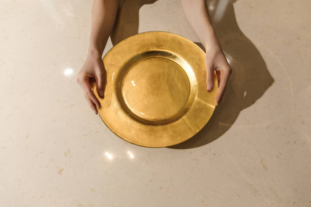 istock Golden metal plate in female hands on light table 965423976