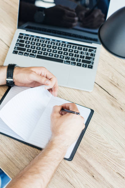 istock high angle view of person writing in blank notebook at workplace 965424218