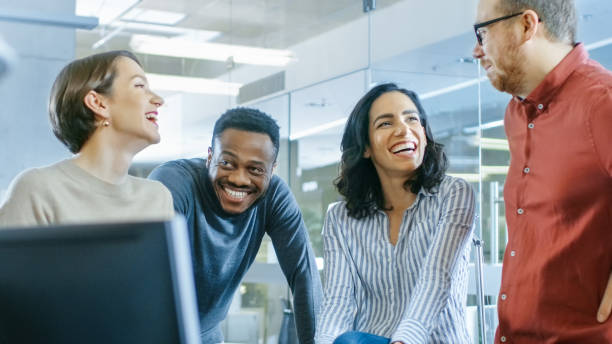 istock Diverse Group of Four Talented Young Professionals Having Team Building Conversation, Joking and Having Fun. Talented Young People in Modern Office. 965424310