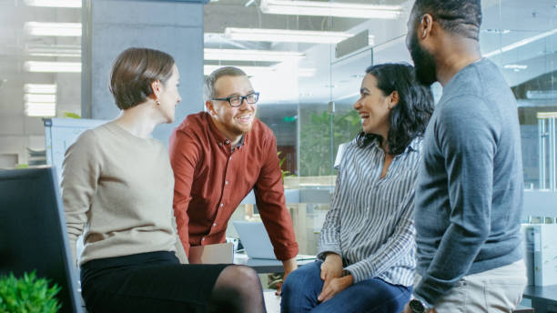 istock Diverse Group of Four Talented Young Professionals Having Team Building Conversation, Joking and Having Fun. Talented Young People in Modern Office. 965424332