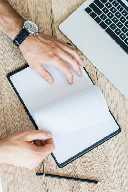 istock partial top view of person holding blank notebook at workplace 965424696