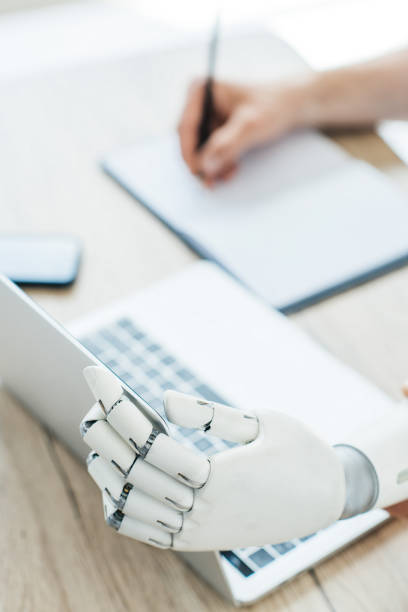 istock close-up view of robotic arm using laptop and human hand taking notes at workplace 965425206