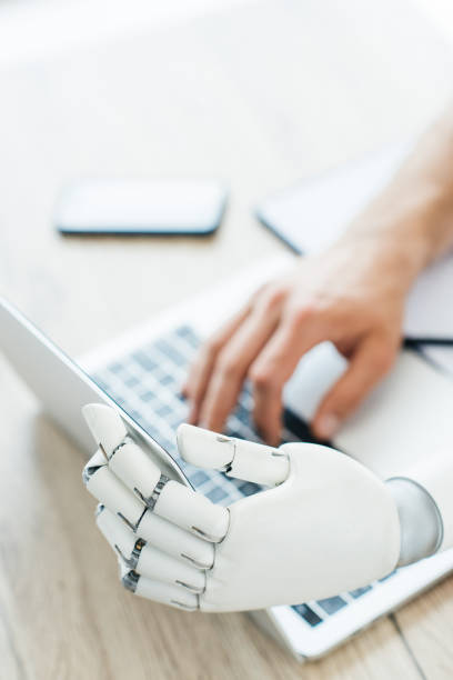 istock selective focus of human and robot hands using laptop at wooden table 965425304