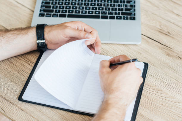 istock partial view of person writing in notebook at wooden table 965425822