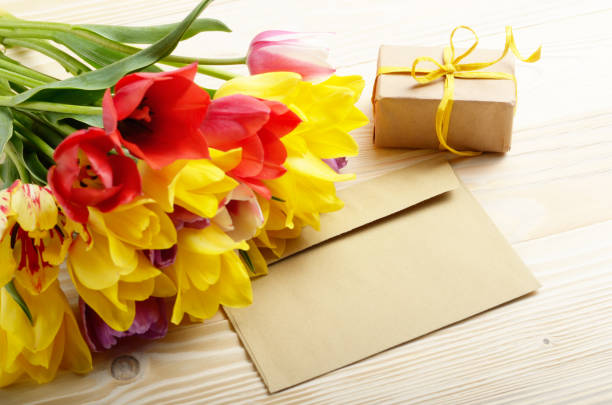 istock Colorful tulips blank envelope and gift box on natural wooden background with space for text 965441082