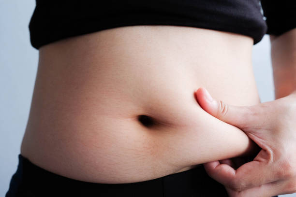 istock woman hand catching fat body belly paunch , diabetic risk factor 965444434