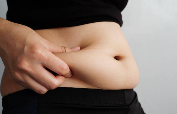 istock Side of woman hand catching fat body belly paunch , diabetic risk factor 965444478