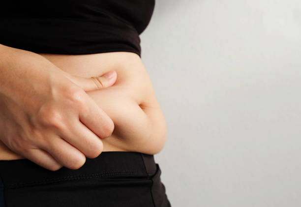 istock Side of woman hand catching fat body belly paunch , diabetic risk factor 965444480