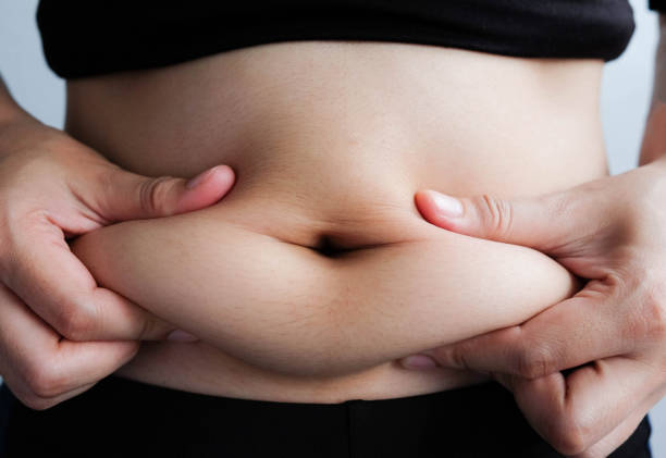 istock woman hand catching fat body belly paunch , diabetic risk factor 965444506