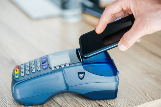 istock cropped shot of person using smartphone and payment terminal 965447734