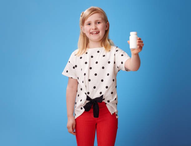 istock smiling modern child showing bottles of vitamins on blue 965451438