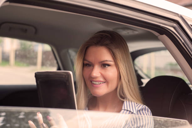 istock Smiling woman in a car with tablet . 965455184