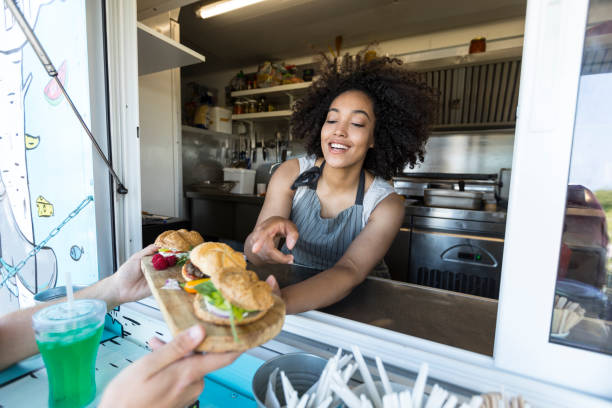 Customer taking burgers from food van Male customer boying sandwiches and burgers from food van. market vendor stock pictures, royalty-free photos & images