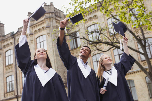 istock Three happy students throwing their mortarboards in the air 965474044