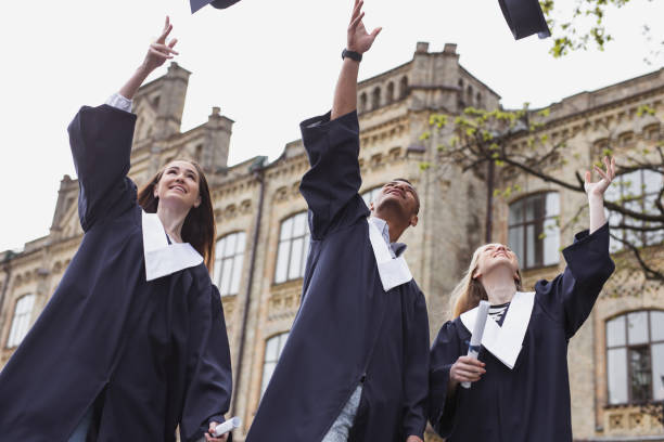 istock Pleasant students throwing mortarboards in the air near university 965474102